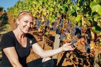 Smiling winemaker Ariel Eberle in the vineyard next to Pinot noir grape cluster.