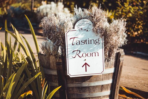 A sign attached to a barrel planter reads 'Tasting Room'.